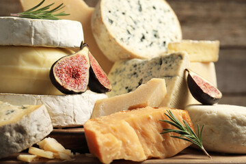 Different types of cheese, figs and rosemary on table, closeup