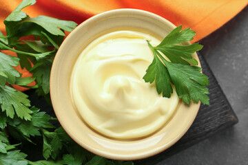Delicious mayonnaise sauce in bowl with parsley on grey table, top view