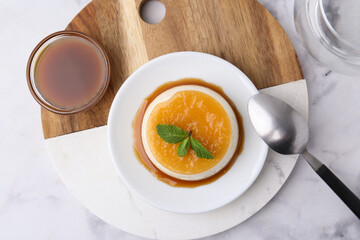 Tasty pudding with caramel sauce served on white marble table, top view