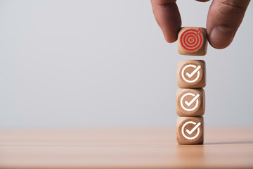 Hand putting red dartboard with arrow on the top of correct sign mark for achievement quality...
