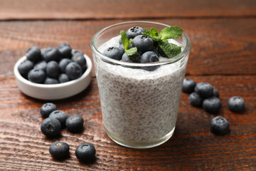 Delicious chia pudding with blueberries and mint in glass on wooden table, closeup