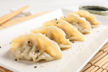 Delicious gyoza dumplings with sesame seeds served on table, closeup