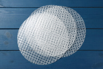 Edible rice paper sheets on blue wooden table, flat lay