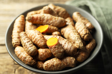 Tumeric rhizomes in bowl on table, closeup