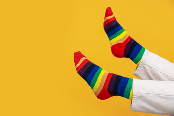 Woman wearing socks in LGBT colors on orange background, closeup. Space for text