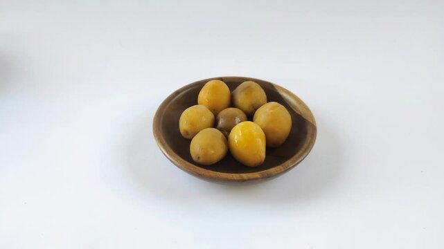 A group of fresh young dates or rutob dates or ruthob dates on a wooden plate with a white background.