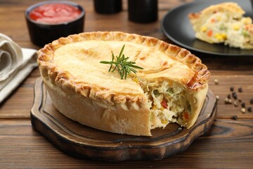 Delicious fresh homemade pie with rosemary on wooden table, closeup