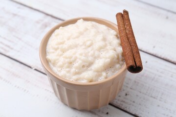 Tasty rice pudding with cinnamon on white wooden table, closeup