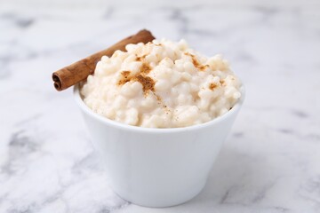 Tasty rice pudding with cinnamon on white marble table, closeup