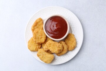Tasty chicken nuggets with sauce on white background, top view