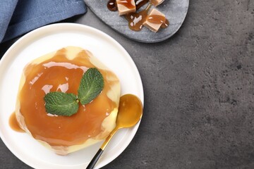 Delicious pudding with caramel sauce and mint served on gray textured table, flat lay. Space for text
