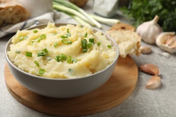 Delicious mashed potato with green onions served on grey table, closeup