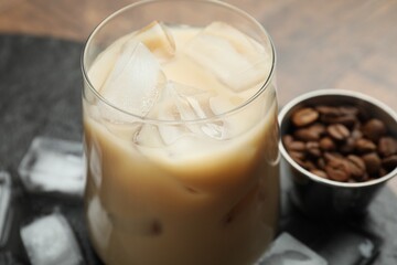 Coffee cream liqueur in glass, ice cubes and beans on table, closeup