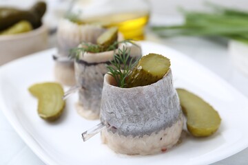 Delicious herring rolls with pickles and dill on table, closeup