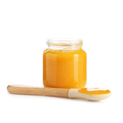 Baby food. Tasty puree in glass jar and spoon isolated on white