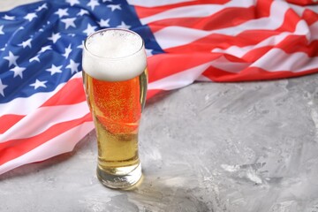 Glass of beer and American flag on grey table. Space for text