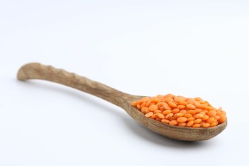 Raw lentils in wooden spoon isolated on white
