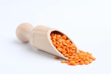 Raw lentils in wooden scoop isolated on white