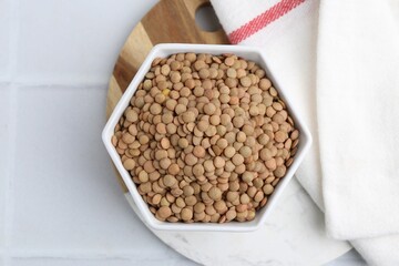 Raw brown lentils on white tiled table, top view