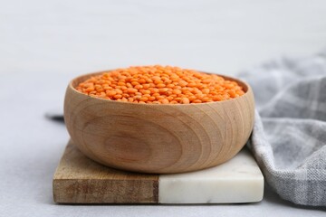Red lentils in bowl on light table, closeup
