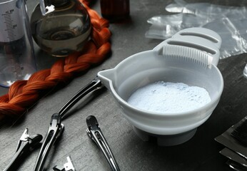 Bleaching powder and hairdresser's tools on black table, closeup
