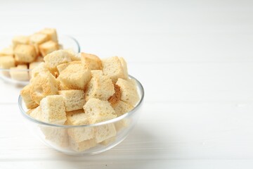 Delicious crispy croutons on white wooden table, closeup. Space for text