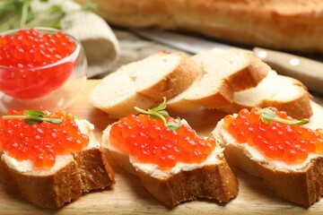 Sandwiches with red caviar and microgreens on wooden table, closeup