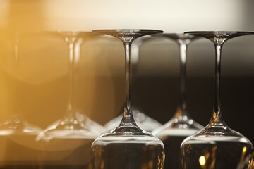 Upturned empty clean glasses on blurred background, closeup. Bokeh effect