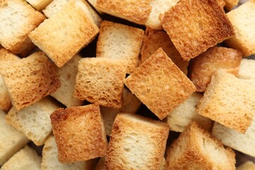 Tasty crispy croutons as background, top view
