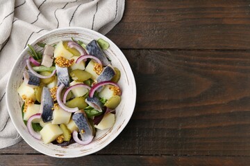 Delicious salad with herring, vegetables and mustard in bowl on wooden table, top view. Space for text