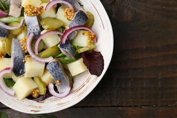Delicious salad with herring, vegetables and mustard in bowl on wooden table, top view. Space for text