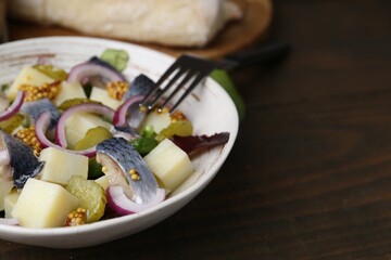Delicious salad with herring, vegetables and mustard in bowl on wooden table, closeup. Space for text