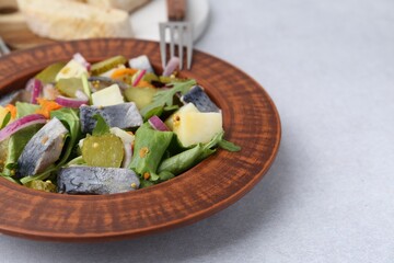 Delicious salad with herring and vegetables on light grey table, closeup. Space for text