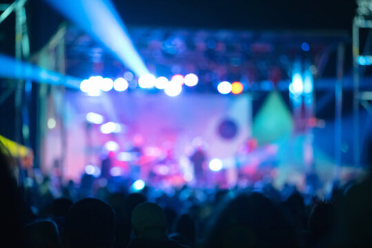 Silhouettes of concert crowd with stage lights, out of focus blu
