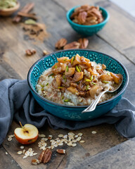 Medium Angled View of an Apple Pecan Oatmeal with Pistachios on a Wooden Table in Indirect Natural Daylight