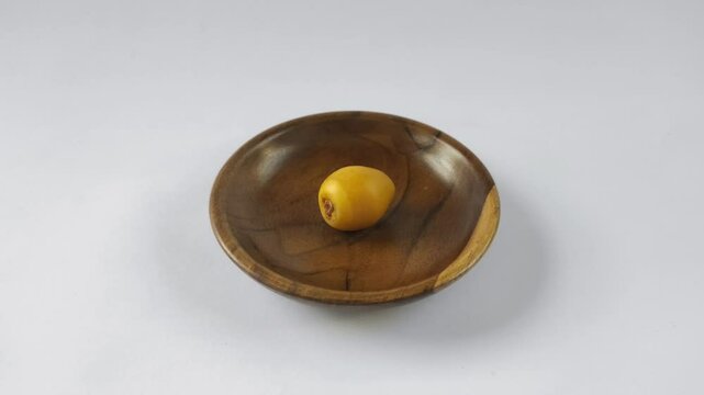 A fresh young dates or rutob dates or ruthob dates on a wooden plate with a white background.