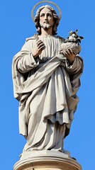 Obraz premium A white stone statue of a man standing against a blue sky