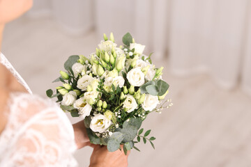 Bride with beautiful wedding bouquet on light background, closeup. Space for text
