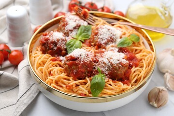 Delicious pasta with meatballs, cheese and basil in bowl on white table, closeup