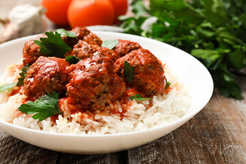 Tasty meatballs with sauce, rice and products on wooden table, closeup