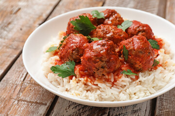 Tasty meatballs with sauce and rice on wooden table, closeup