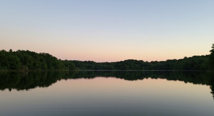 Obraz premium Tranquil Twilight Reflections: A Serene Lake Surrounded by Lush Greenery Under a Soft Sky