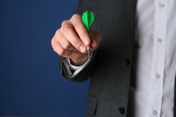 Fototapeta premium Man holding dart on blue background, closeup