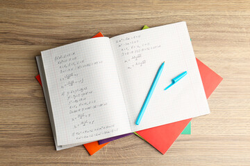 Doing homework. Copybook with math assignment and stationery on wooden table, top view