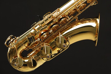 Fototapeta premium Jazz. One beautiful saxophone on black background, closeup
