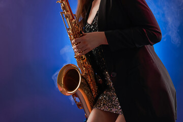 Professional musician playing saxophone on color background with smoke, closeup