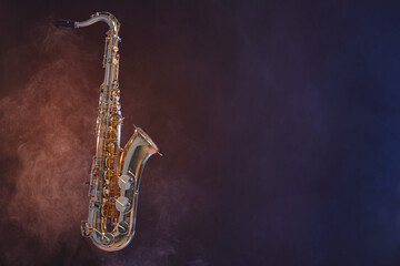 Fototapeta premium Golden saxophone on dark background with smoke. Space for text