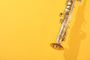 Golden soprano saxophone on yellow background, closeup. Space for text