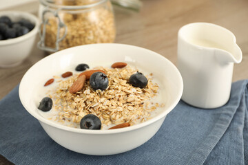Tasty oatmeal with milk, blueberries and almonds in bowl on table, closeup