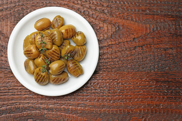 Grilled green olives on wooden table, top view. Space for text